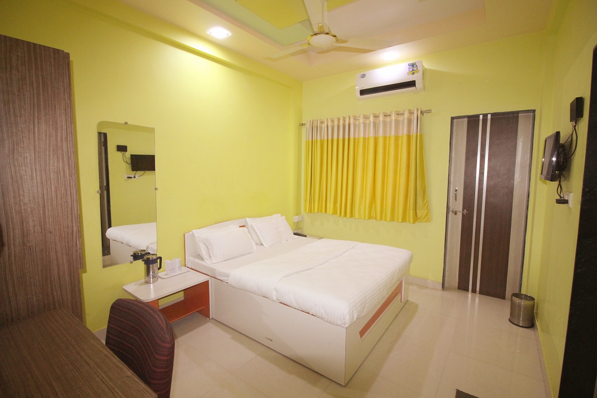 Double AC room at Hotel Somnath Sagar showcasing in-room amenities like bedside tables and lighting.